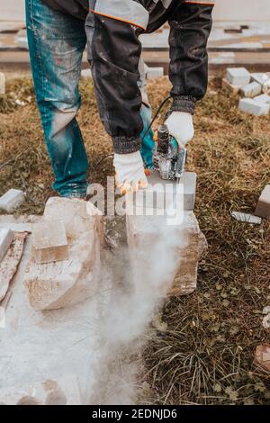 Maurer schneidet Stein mit Winkelschleifer - schnell und sicher - Staub von Elektrowerkzeugen Stockfoto