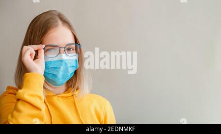 Neblige Brille trägt auf junge Frau. Teenager-Mädchen in blau medizinische Schutzmaske und Brillen wischt verschwommen neblig vernebelte Gläser. Neuer Normalwert Stockfoto