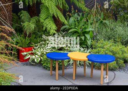 Moderne Gartenbank Sitzbereich auf Steinplatten gepflasterte Terrasse mit einer grünen Grenze, Hampton Court Flower Show London England Großbritannien Stockfoto