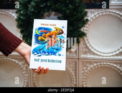 Paris, Frankreich - 14. Feb 2021: POV Frau hält mit Riesenofen Weihnachten Hintergrund das Buch von Nikolai Gogol in der Nacht vor Weihnachten Stockfoto