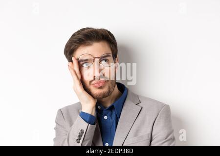 Nahaufnahme eines schockierten müden Büroangestellten nimmt eine Brille ab und starre in die obere rechte Ecke mit traurigem Gesicht, weißem Hintergrund Stockfoto