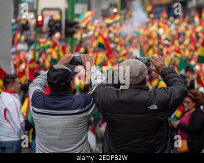 Zwei Männer fotografieren Massen von Demonstranten nach dem Rücktritt von Präsident Evo Morales in La Paz, Bolivien, 10. November 2019. Stockfoto