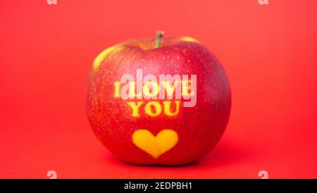 Valentinstag themed Apfel mit I Love You Nachricht und Ein Herzsymbol auf einem roten Hintergrund Stockfoto