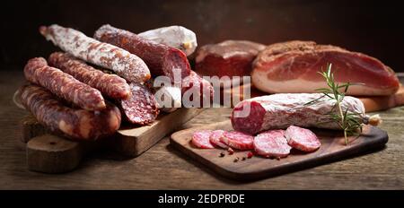 Verschiedene Arten von Salami, Speck und Würstchen auf einem Holztisch Stockfoto