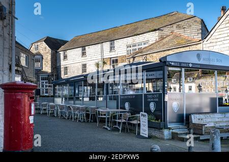 Riesiges Restaurant im Freien in Padstow, in der Regel voller Touristen, jetzt völlig leer wegen 2021 Pandemie Sperre. Roter Briefkasten im Vordergrund Stockfoto