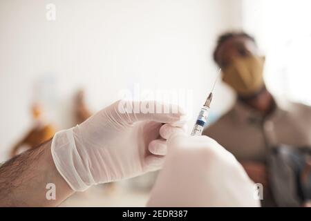 Nahaufnahme eines nicht erkennbaren männlichen Arztes, der die Spritze hält, während Patienten in der medizinischen Klinik impft, Platz kopieren Stockfoto