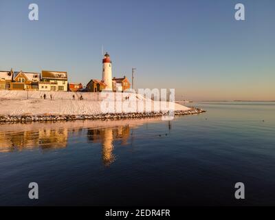 Schneebedeckter Strand während wnter von Urk Leuchtturm in den Niederlanden. Kaltes Winterwetter in den Niederlanden Stockfoto