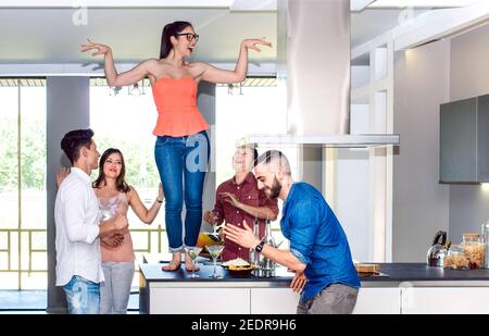 Frau tanzt auf dem Tisch mit Freunden Gruppe zu Hause Cocktail Bar mit Aperitif vor dem Abendessen in der Happy Hour - betrunken Verrückte Menschen verbringen Zeit zusammen Stockfoto