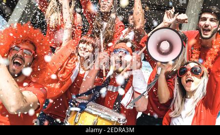 Freunde Fußball Fan Fans jubeln mit Konfetti beim Fußballspiel Veranstaltung im Stadion - Gruppe der Jugendlichen mit roten T-Shirts Stockfoto