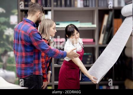 Junge Familie Mann und Frau, wählen Sie Tapete für Wände in neue Wohnung aus Katalog. Home Lifestyle Renovierungskonzept. Stockfoto