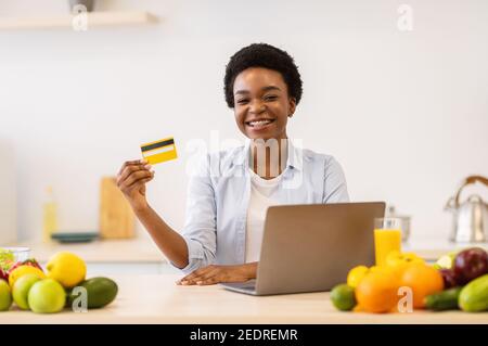 African American Frau Tun Lebensmittel Online-Shopping In Der Modernen Küche Stockfoto