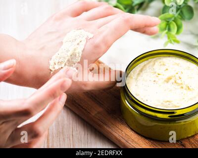 Weibliche Hände halten feuchtigkeitsspendende Körpercreme oder Peeling Stockfoto