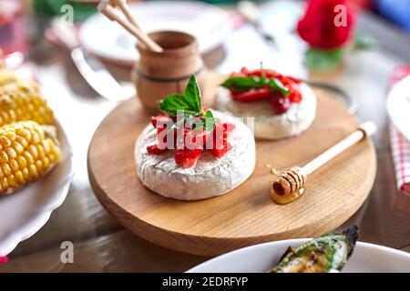 Gegrillter Camembert-Käse mit Erdbeer-, Honig- und Basilikumblättern, Delikatessen, Camembert-Käsefondue auf dem Esstisch. Stockfoto