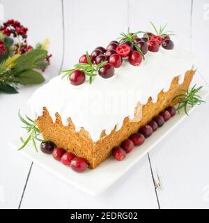 Englischer Kuchen auf einem weißen Teller mit Preiselbeeren und Rosmarin. Weihnachtskuchen. Stockfoto