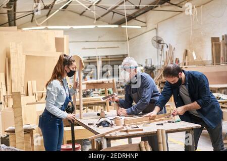 Handwerker Team mit Gesichtsmasken wegen Covid-19 in der Schreinerei Stockfoto