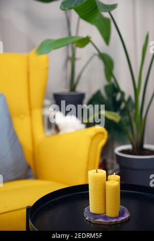 Gelbe Kerze aus Bienenwachs mit Duft von Honig auf Nachttisch im Schlafzimmer skandinavischen Interieur. Stockfoto