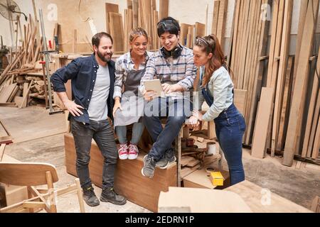 Gruppe von Handwerkern in der Ausbildung auf Tablet-Computer in der Werkstatt Stockfoto