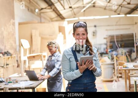 Lächelnde Handwerker Frau in der Schreinerei mit Tablet-Computer Stockfoto