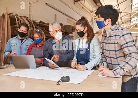 Handwerker Team mit Gesichtsmasken wegen Covid-19 in einem Besprechung Stockfoto