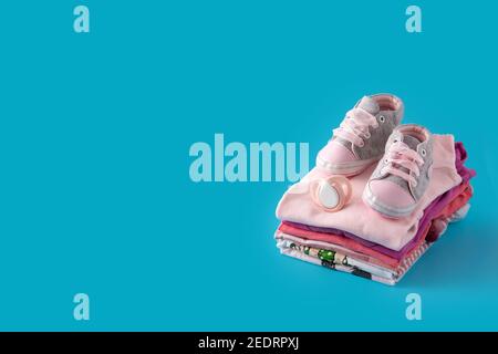 Baby Strampler und Babyschuhe auf blauem Hintergrund Stockfoto