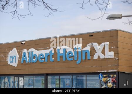 ZUTPHEN, NIEDERLANDE - 09. Feb 2021: Schnee auf Name und Logo einer großen holländischen Supermarktkette nach einem Schneesturm gegen einen blauen Himmel mit Wolkenbildung Stockfoto