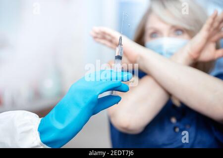 Menschen Impfung Phobie Konzept. Ältere ältere Frau verweigert Spritze mit Impfstoff. Stockfoto