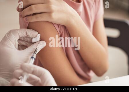 Nahaufnahme eines nicht erkennbaren Arztes, der das Kind in der medizinischen Klinik impft, Kopierraum Stockfoto