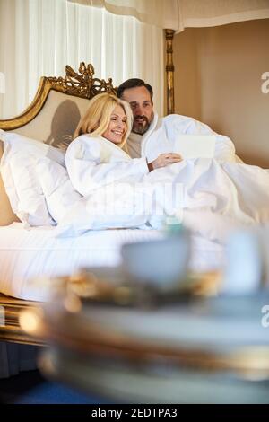 Entspanntes Paar, das sich in einem gemütlichen weißen Bett ausruhen kann Stockfoto