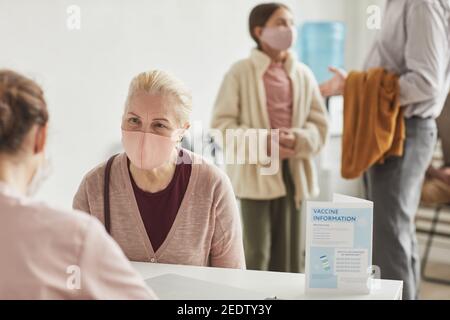 Porträt einer weißhaarigen älteren Frau mit Maske bei der Registrierung für covid-Impfstoff in der medizinischen Einrichtung, Kopierer Platz Stockfoto