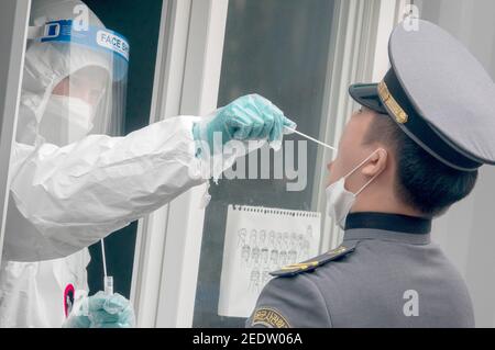 Seoul, Südkorea. Februar 2021, 14th. Eine Krankenschwester, die einen persönlichen Schutzanzug (PSA) trägt, nimmt während eines kostenlosen covid-19-Tests in einer provisorischen Klinik eine Abstrichprobe von einem Kadett der Korea Military Academy. Kredit: SOPA Images Limited/Alamy Live Nachrichten Stockfoto