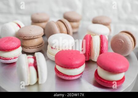 Koch-, Süßwaren- und Backkonzept - bunte rote, weiße und karamellfarbene Macarons auf dem Tisch Stockfoto