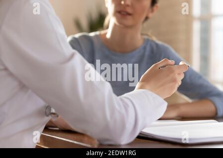 Nahaufnahme der jungen Hausärztin, die gestikulierend mit dem Patienten kommuniziert. Stockfoto