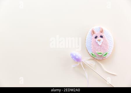 Handgefertigter Llama-geformter Plätzchen mit pastellfarbenem Spielzeug-Ei auf einem Stock auf einem pastellfarbenen Hintergrund. Ostern Minimal Konzept. Flach liegend Stockfoto