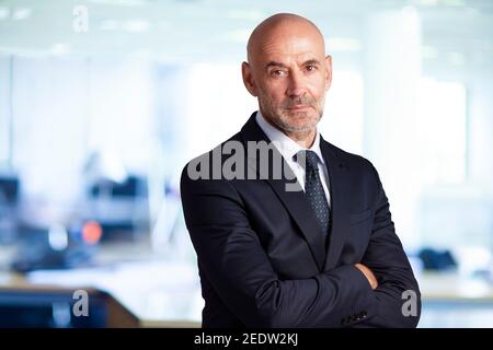 Porträtaufnahme eines älteren Geschäftsmannes, der mit gekreuzten Armen im Büro steht. Stockfoto