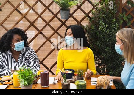 Multirassische Freunde mit gesunden Mittagessen in Kaffee Brunch Bar während Ausbruch des corona-Virus Stockfoto