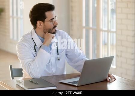 Nachdenklicher junger Hausarzt, der in der Ferne schaut. Stockfoto