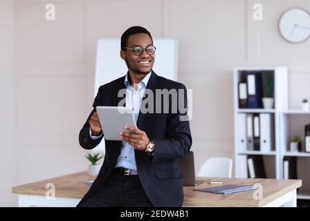 Fröhliche afroamerikanische junge Geschäftsmann mit digitalen Tablet im Büro Stockfoto