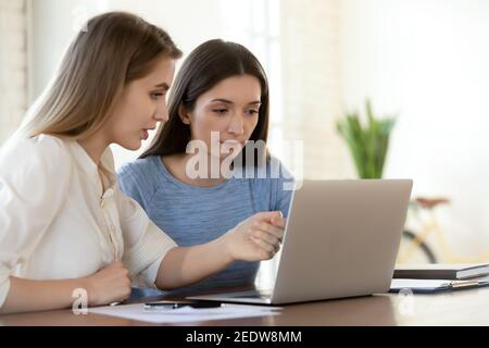 Junge Führungspersönlichkeit, die jungen Kollegen hilft. Stockfoto