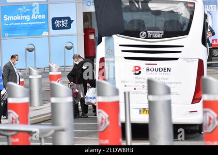 Nach der Landung in England verlassen zwei Passagiere den Flughafen Birmingham an Bord eines Busses. Neue Vorschriften, die jetzt in Kraft sind, verlangen, dass jeder, der sich vor kurzem an einem Ort mit hohem Risiko befindet, über einen bestimmten Hafen nach England einreist und ein Paket im Voraus gebucht hat, in einer der von der Regierung verwalteten Quarantäneeinrichtungen übernachtet. Bilddatum: Montag, 15. Februar 2021. Stockfoto