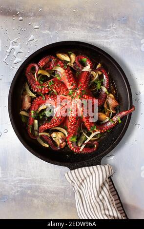 Octopus Lagareiro Stil gekleidet mit Zwiebeln und garlics Nelken auf einem gealterten Metalltisch. Portugiesische Küche. Stockfoto