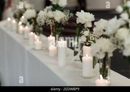 Tischeinstellung bei Hochzeitsempfang. Modernes Veranstaltungsdesign. Florale Kompositionen mit schönen Blumen und Grün, Kerzen auf dekorierten Tisch. Tisch se Stockfoto