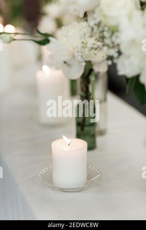 Tischeinstellung bei Hochzeitsempfang. Modernes Veranstaltungsdesign. Florale Kompositionen mit schönen Blumen und Grün, Kerzen auf dekorierten Tisch. Tisch se Stockfoto