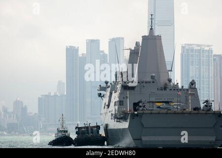 Blick auf das Amphibiendock-Landungsschiff USS Green Bay (LPD 20) vor der Skyline von Gebäuden, angedockt am Eingang zum Victoria Harbour im Rahmen eines planmäßigen Hafenbesuchs. Green Bay ist Teil der Bonhomme Richard Expeditionary Strike Group, die hier in Hongkong, Hongkong, SAR, China, VR China, zu sehen ist. © Time-Snaps Stockfoto