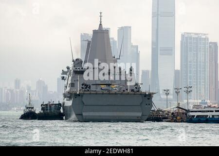 Blick auf das Amphibiendock-Landungsschiff USS Green Bay (LPD 20) vor der Skyline von Gebäuden, angedockt am Eingang zum Victoria Harbour im Rahmen eines planmäßigen Hafenbesuchs. Green Bay ist Teil der Bonhomme Richard Expeditionary Strike Group, die hier in Hongkong, Hongkong, SAR, China, VR China, zu sehen ist. © Time-Snaps Stockfoto