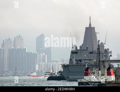 Blick auf das Amphibiendock-Landungsschiff USS Green Bay (LPD 20) vor der Skyline von Gebäuden, angedockt am Eingang zum Victoria Harbour im Rahmen eines planmäßigen Hafenbesuchs. Green Bay ist Teil der Bonhomme Richard Expeditionary Strike Group, die hier in Hongkong, Hongkong, SAR, China, VR China, zu sehen ist. © Time-Snaps Stockfoto