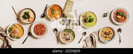 Flache vegetarische cremige hausgemachte Suppe und Löffel auf weißem, schlichten Tischhintergrund, Draufsicht. Herbst und Winter cremige vegane Suppen, Herbst und Winter vegetarisches Menükonzept Stockfoto