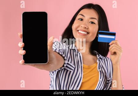 Asiatische Dame zeigt leere Smartphone-Bildschirm und Kreditkarte Stockfoto