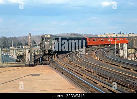 Ein U-Bahn-Zug auf einem erhöhten Abschnitt des New Yorker U-Bahn-Systems – kurz vor der East Tremont Avenue – West Farms Square Station in Richtung Manhattan und South Ferry auf der Linie 5 Lexington, New York, USA 1969. Der Zug enthält einige markante rote Kutschen. Im Hintergrund sind die Bäume des Brooklyn Park zu sehen. Stockfoto