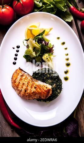 Gebackenes Lachssteak mit Spinat und Zitronenscheibe Stockfoto