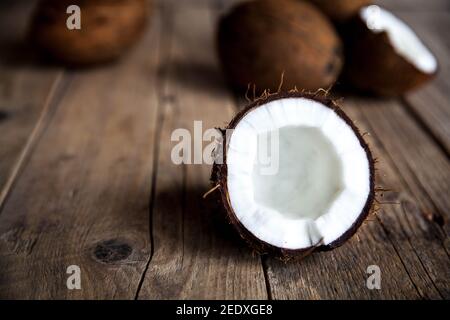 Reif halb Kokosnuss auf einem hölzernen Hintergrund. Reif halb Kokosnuss auf einem hölzernen Hintergrund. Coconut Creme und Öl. Stockfoto